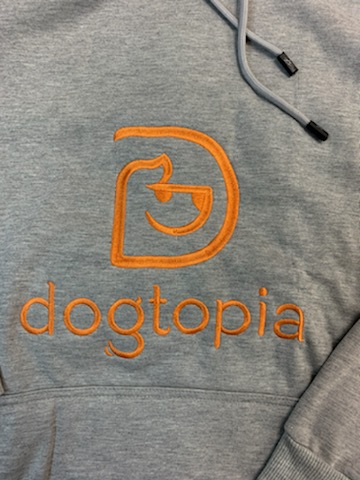 Soft light gray hoodie close-up view of Dogtopia in orange